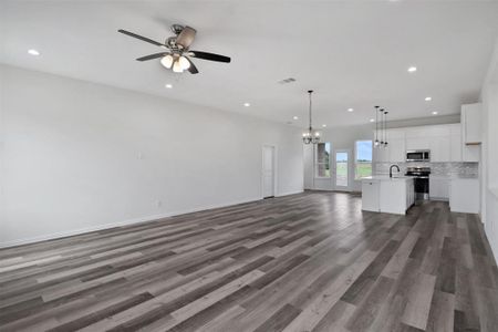 Unfurnished living room with sink, wood-type flooring, and ceiling fan with notable chandelier