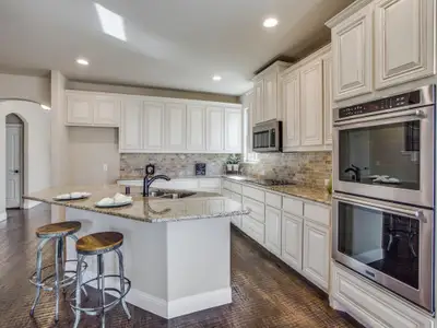 Kitchen featuring sink, tasteful backsplash, a kitchen island with sink, appliances with stainless steel finishes, and light stone countertops