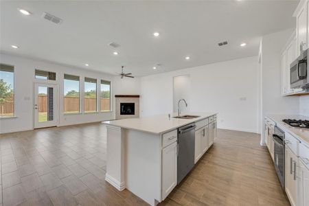 Kitchen featuring white cabinets, appliances with stainless steel finishes, sink, an island with sink, and ceiling fan