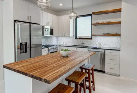 Kitchen featuring butcher block countertops, a breakfast bar, a sink, appliances with stainless steel finishes, and backsplash