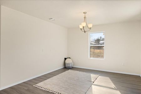 Empty room with dark hardwood / wood-style floors and a chandelier