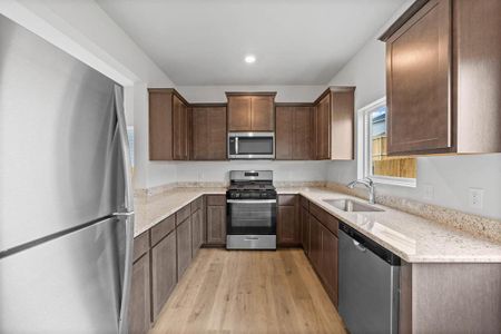 Kitchen featuring light wood-style flooring, recessed lighting, a sink, appliances with stainless steel finishes, and light stone countertops