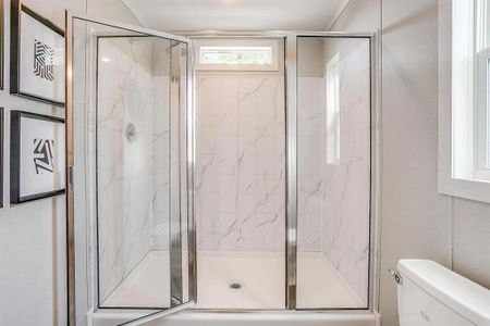 Bathroom featuring toilet and a shower with shower door