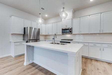 Kitchen with visible vents, an island with sink, a sink, stainless steel appliances, and light wood-style floors