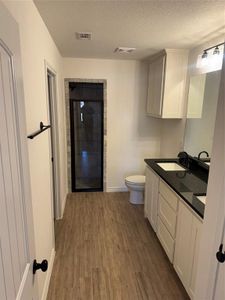 Bathroom featuring wood-type flooring, toilet, a textured ceiling, and vanity