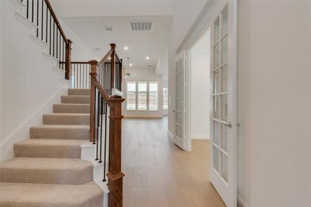 Staircase featuring wood-type flooring, french doors, and ceiling fan