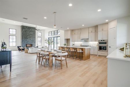 Dining area with visible vents, light wood-style flooring, a high end fireplace, recessed lighting, and ceiling fan