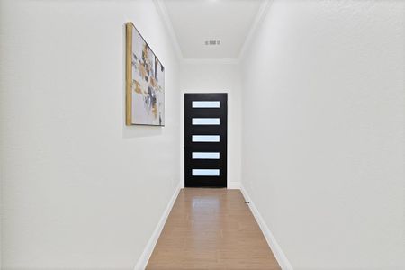 Doorway to outside with wood-type flooring and crown molding