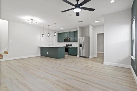 Kitchen featuring decorative backsplash, an island with sink, decorative light fixtures, light hardwood / wood-style floors, and stainless steel appliances