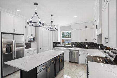 Under-cabinet lighting is included in the whole kitchen along with soft closing cabinets and drawers. Stunning black features showcasing a herringbone subway tile backsplash and kitchen island with brushed gold handles.