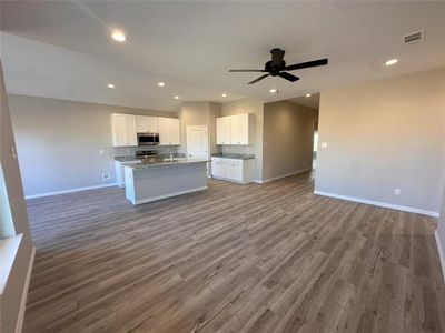 Kitchen with ceiling fan, hardwood / wood-style flooring, appliances with stainless steel finishes, and white cabinetry