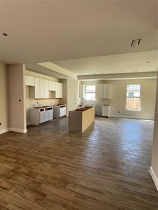 Unfurnished living room with a healthy amount of sunlight and dark hardwood / wood-style flooring