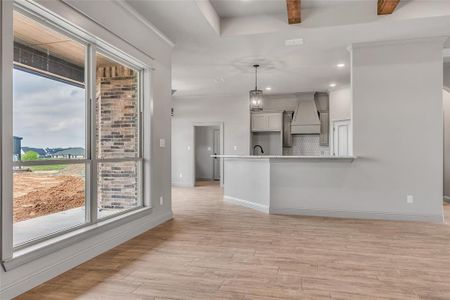 Kitchen featuring custom range hood, decorative backsplash, white cabinets, pendant lighting, and light hardwood / wood-style flooring