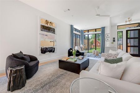 Living room with floor to ceiling windows, wood-type flooring, and ceiling fan