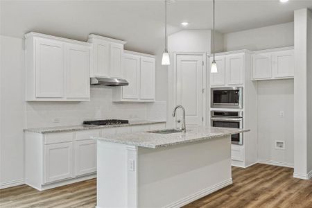 Kitchen featuring decorative light fixtures, wood-type flooring, appliances with stainless steel finishes, and white cabinetry