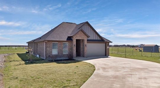 View of front of property with a garage, concrete driveway, a front yard, board and batten siding, and brick siding