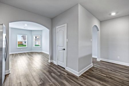 Empty room with baseboards, arched walkways, and dark wood finished floors