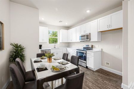 Kitchen with dark hardwood / wood-style floors, stainless steel appliances, white cabinets, and sink