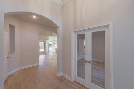 Corridor with light hardwood / wood-style flooring and french doors