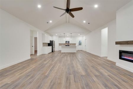 Unfurnished living room featuring light hardwood / wood-style flooring, lofted ceiling, and ceiling fan