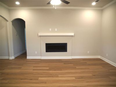 Unfurnished living room featuring ornamental molding, hardwood / wood-style flooring, and ceiling fan