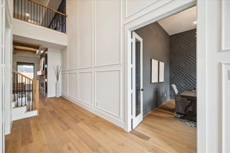 The two-story foyer, with its soaring ceilings, showcases elegant wall paneling.