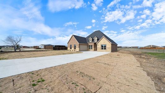 View of front of house featuring brick siding, a shingled roof, concrete driveway, fence, and a garage