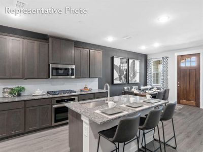 Kitchen with a kitchen island with sink, light stone counters, a breakfast bar, appliances with stainless steel finishes, and light hardwood / wood-style floors