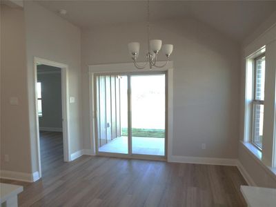 Unfurnished dining area with vaulted ceiling, hardwood / wood-style flooring, and a notable chandelier