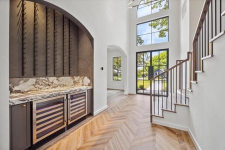 Your front entry has an abundance of natural light and soaring ceilings with steel framed double wide doors and a formal dining on the right hand side before the wine bar with double wine refrigerators, marble counters, and plenty of wine rack storage. The European oak wood floors with chevron-pattern add an element of elegant design.