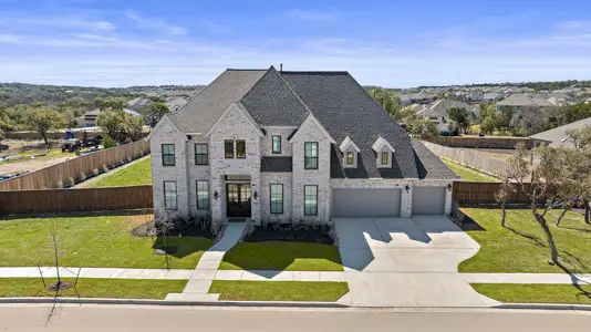 French country home featuring driveway, fence private yard, a front lawn, and brick siding