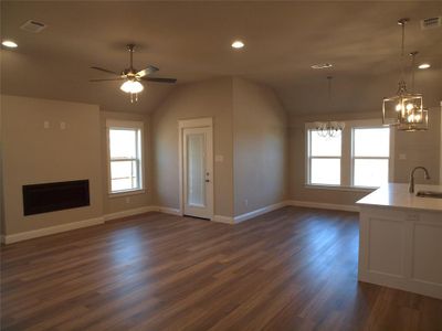 Unfurnished living room featuring lofted ceiling, sink, plenty of natural light, and dark hardwood / wood-style floors