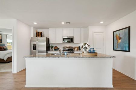 Kitchen with an island with sink, stainless steel appliances, white cabinetry, and light hardwood / wood-style floors