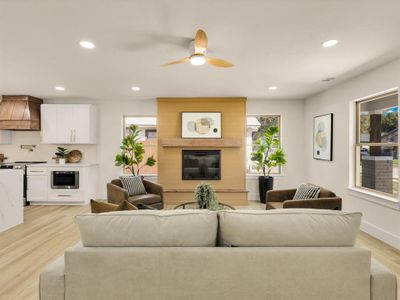 Living room with light hardwood / wood-style flooring, ceiling fan, and a fireplace