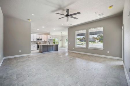 Unfurnished living room with sink, ceiling fan, and plenty of natural light