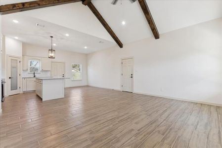 Unfurnished living room with beam ceiling, high vaulted ceiling, and light wood-type flooring