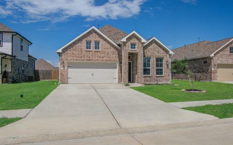 This is a modern single-family home featuring a two-story design with a brick facade, an attached two-car garage, and a neatly manicured lawn. The home is situated in a suburban neighborhood with close proximity to neighboring houses.