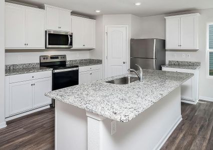 Kitchen with granite countertops, white cabinets with hardware, stainless steel appliances and vinyl flooring.