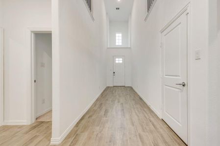 Hall featuring a high ceiling and light wood-type flooring