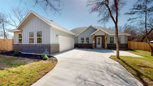 View of front of property featuring brick siding, board and batten siding, an attached garage, and fence