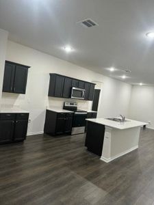 Kitchen with an island with sink, appliances with stainless steel finishes, sink, and dark wood-type flooring