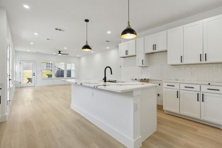 Kitchen with light hardwood / wood-style flooring, white cabinets, a kitchen island with sink, and sink