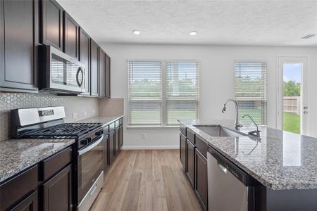 This kitchen is by far any chef’s dream! This spacious kitchen features high ceilings, dark stained wood cabinets, granite countertops, SS appliances, modern tile backsplash, recessed lighting, extended counter space, granite kitchen island with double sink, space for breakfast bar, and a walk-in pantry all overlooking your huge family room.