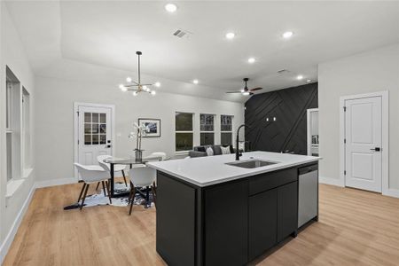 Kitchen featuring a kitchen island with sink, sink, pendant lighting, light hardwood / wood-style flooring, and dishwasher