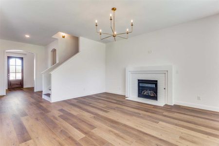 Unfurnished living room with hardwood / wood-style floors, a fireplace, and a chandelier