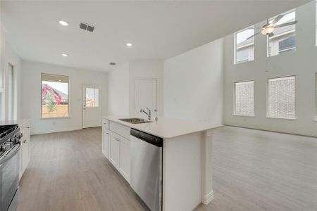 Kitchen featuring white cabinetry, sink, an island with sink, light hardwood / wood-style floors, and appliances with stainless steel finishes