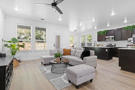 Living room with a wealth of natural light, sink, light hardwood / wood-style flooring, and ceiling fan