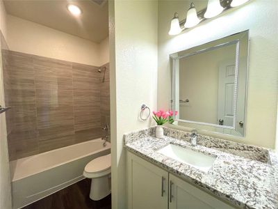 Full bathroom featuring tiled shower / bath, vanity, wood-type flooring, and toilet