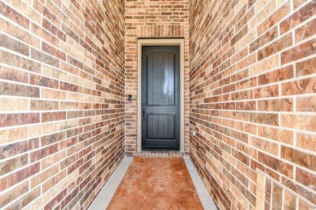 This photo features a welcoming entryway with a dark wooden door framed by warm-toned brick walls. The pathway is accented by a brown doormat, providing a cozy entrance to the home. This photo features a welcoming entryway with a dark wooden door framed by warm-toned brick walls. The pathway is accented by a brown doormat, providing a cozy entrance to the home.