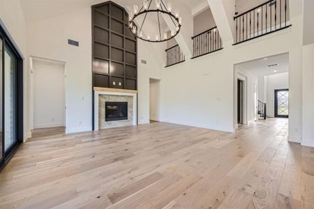 Unfurnished living room featuring light wood-type flooring, a high ceiling, and plenty of natural light